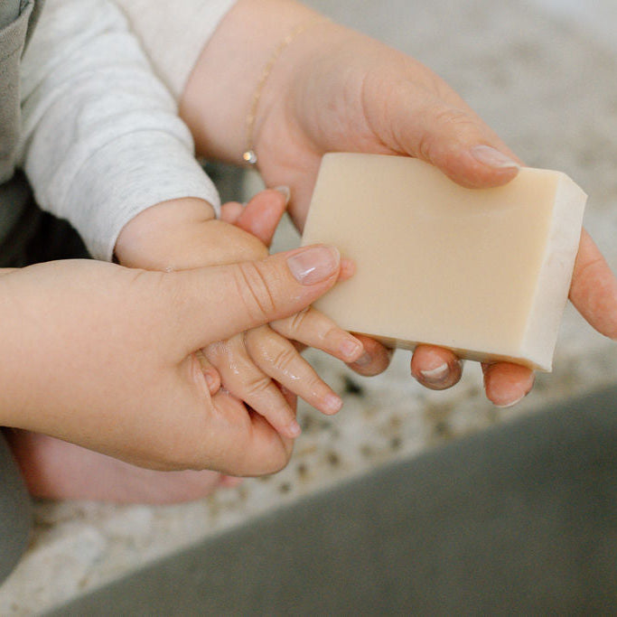 Person holding a bar of soap with a child's hand